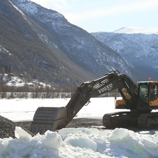 Gravemaskin Volvo EC 380i arbeid om vinteren med fjell i bakgrunnen