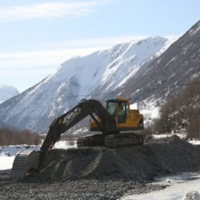 Gravemaskin Volvo EC 210 B står på toppen av en haug av grus