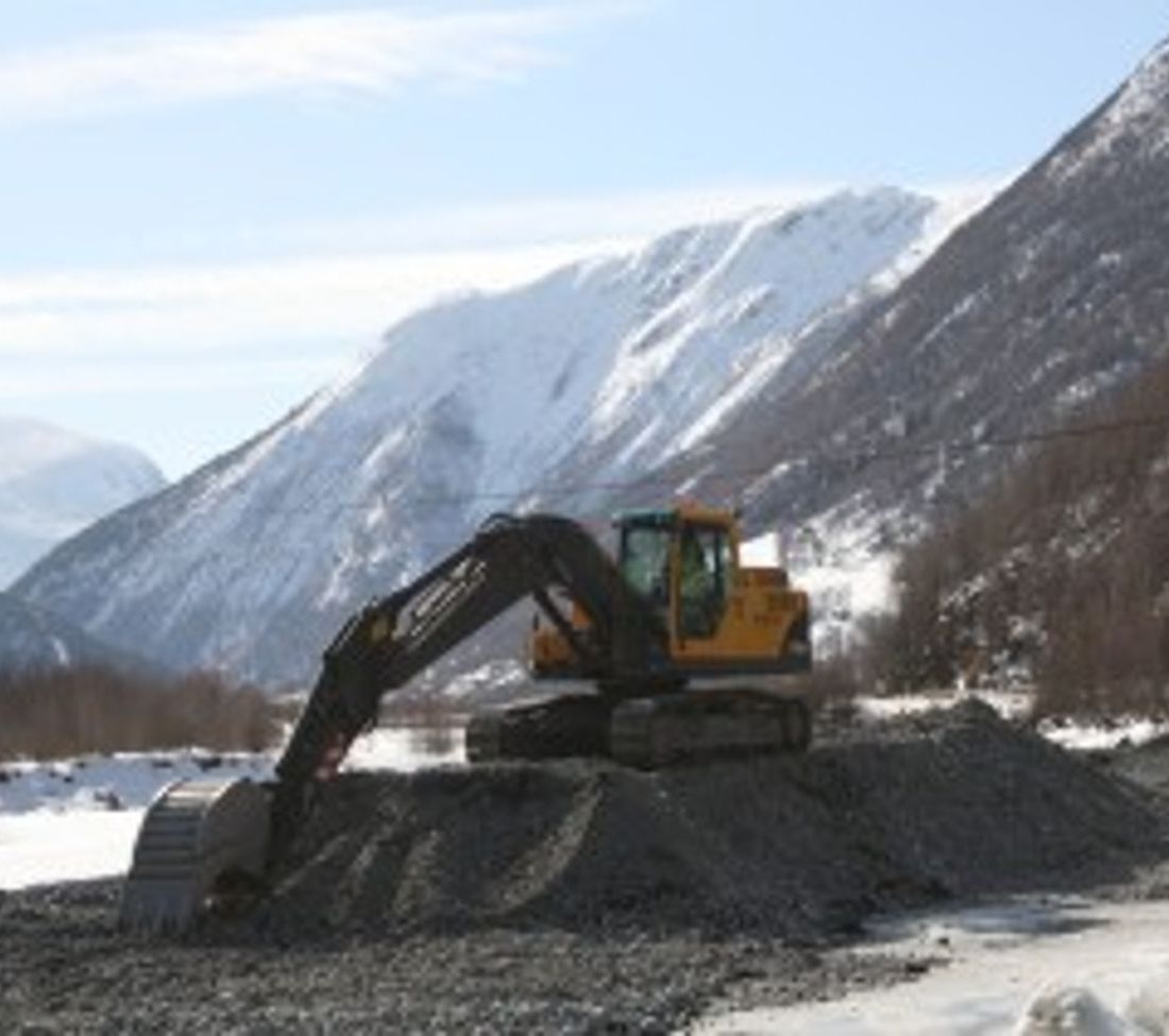 Gravemaskin Volvo EC 210 B står på toppen av en haug av grus